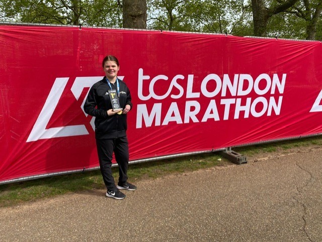 Olivia standing in front of the mini marathon flag